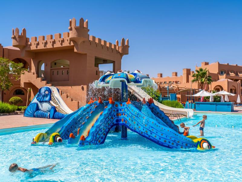 Kinderen spetteren in water met een kleurrijke octopus waterpret bij het vakantieoord onder een blauwe lucht.