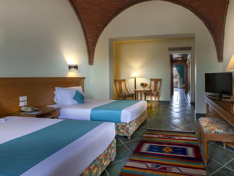 Hotelkamer met twee eenpersoonsbedden, tapijt en zithoek.