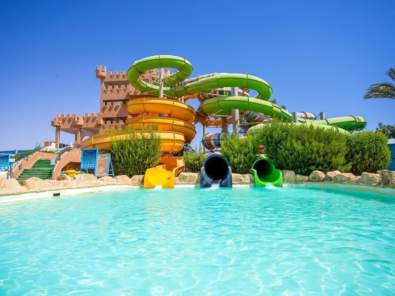 Waterpark met kleurrijke glijbanen en helder zwembad onder blauwe lucht