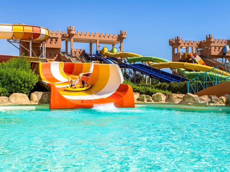 Kleurrijke glijbanen leiden in een helder zwembad op een zonnige dag.