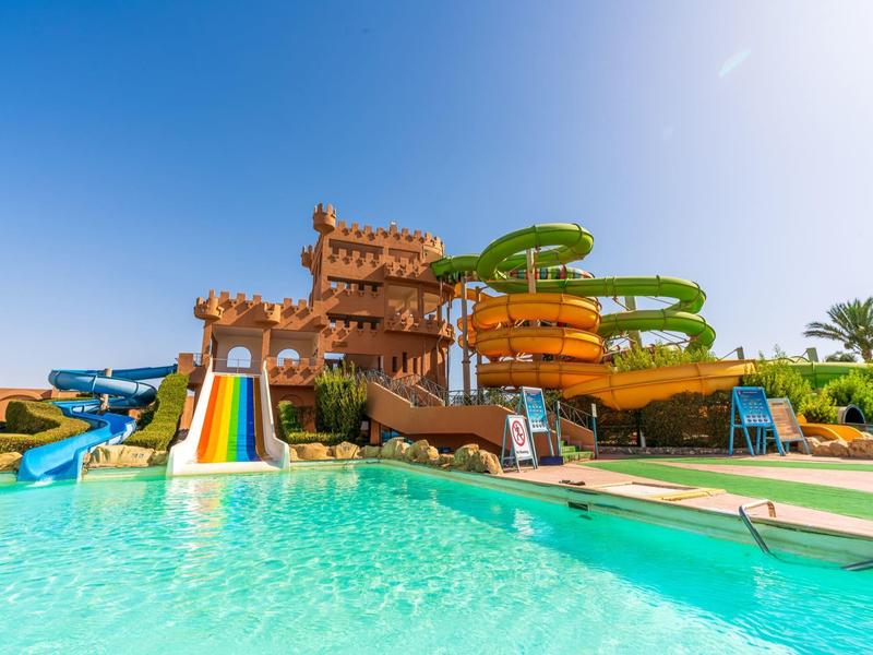 Kleurrijke waterglijbanen leiden in een helder zwembad onder een blauwe lucht op een zonnige dag.