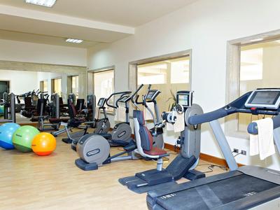 Helles Fitnessstudio mit Laufbändern, Ergometern, bunten Gymnastikbällen und Spiegelwand.