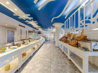 Buffetbereich mit blauer Decke, weißen Tischen, viel Essen und modernem, hellem Design.