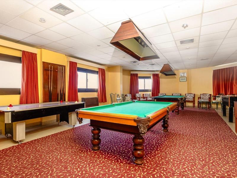 Spiellokal mit grünem Billardtisch, Airhockey-Tisch, roten Vorhängen und Teppichboden.