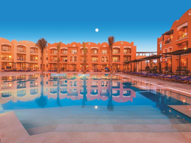 Avondzicht op een hotel met zwembad, heldere lucht en maanlicht.