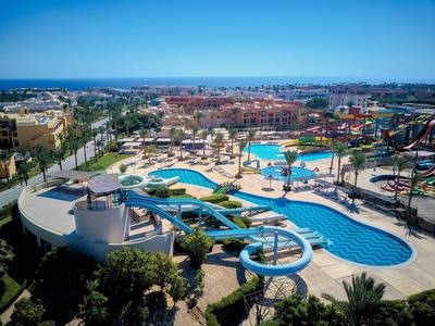 Großer Wasserpark mit mehreren Pools, Wasserrutschen und Sonnenschirmen in einer Ferienanlage.
