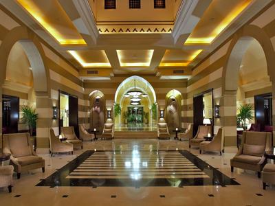 Ein luxuriöser Hotellobby mit hohen Decken, eleganten Säulen, Sitzbereichen und warmem Licht.