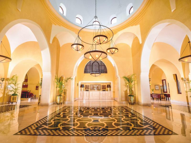 Bright hotel lobby with high vaulted ceilings and decorative marble floor.
