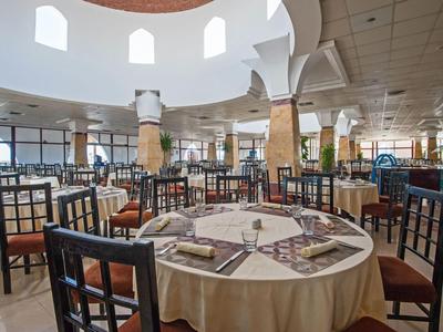 Großzügiges Restaurant mit runden Tischen und Holzstühlen unter einer Kuppel mit großen Fenstern