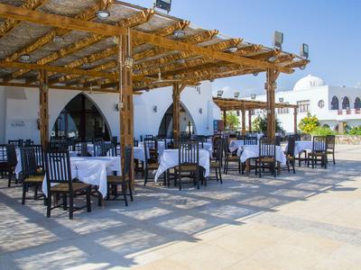 Freiluftrestaurant mit verschatteten Tischen und Stühlen unter einem Holzpergola.