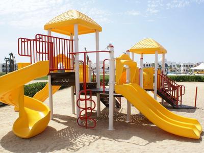 Aire de jeux colorée avec deux toboggans et structures d'escalade sur sable extérieur.