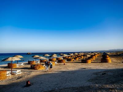 Strand mit Liegestühlen und Sonnenschirmen bei klarem Himmel am Meer