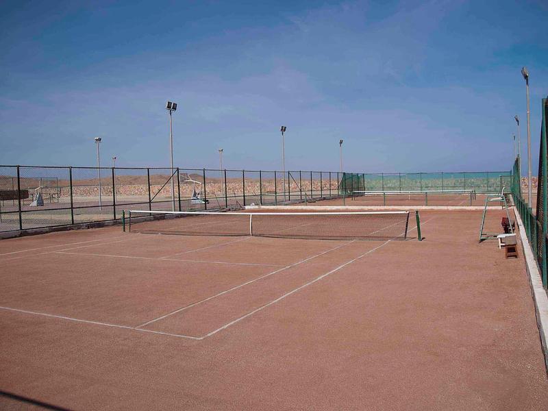 Terrain de tennis extérieur près de la plage avec clôture et vue sur la mer