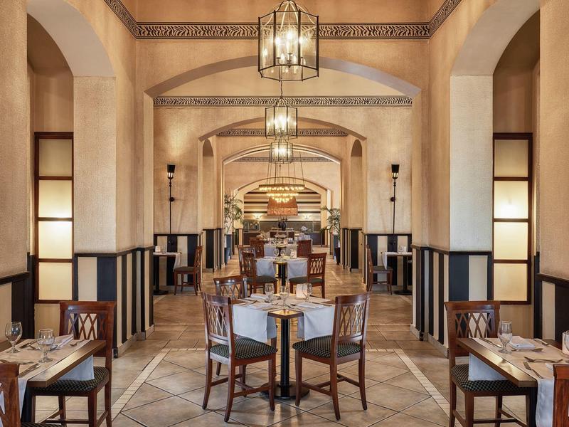 Elegant restaurant with wooden tables and comfortable chairs in a warm, Mediterranean setting.