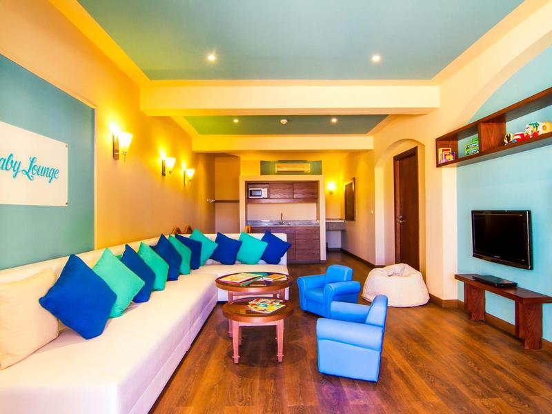 Bright living room with long sofa, colorful cushions, and wooden floor in a modern apartment.