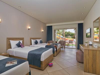 Habitación de hotel con dos camas, decoración moderna, con acceso a terraza y vista al jardín.