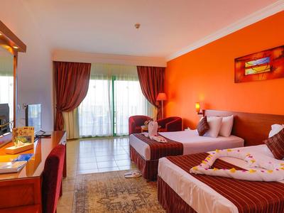 Habitación de hotel acogedora con dos camas, escritorio, cortinas y cálida pared en color naranja.