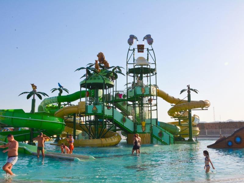 Niños jugando en un parque acuático con toboganes y juegos de agua en un día soleado.
