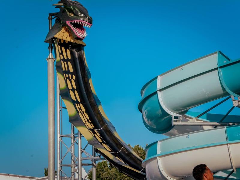 Parque acuático con un tobogán de agua largo negro y amarillo bajo un cielo azul.