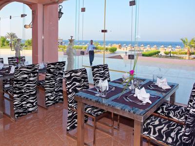 Terrasse mit Tischen und Stühlen in Zebra-Muster, Blick aufs Meer und blauer Himmel im Hintergrund.