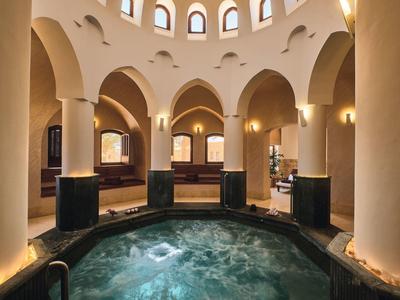 Jacuzzi redondo en un spa elegante y luminoso con arcos y columnas.