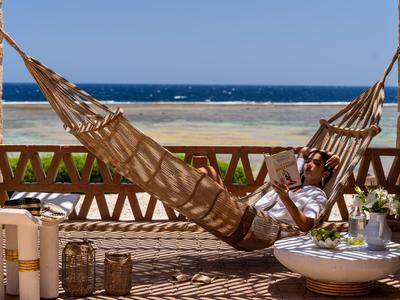Personne se détendant dans un hamac avec vue sur la mer depuis une terrasse.
