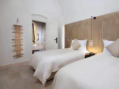 Habitación de hotel moderna con dos camas individuales y un interior cálido y luminoso.