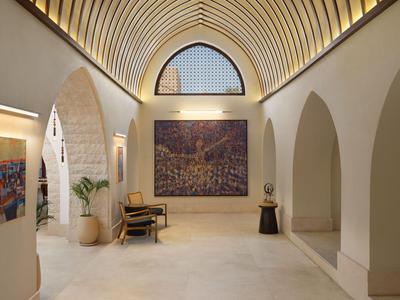 Couloir d'hôtel élégant avec arches de fenêtres courbées, œuvres d'art et éclairage moderne.