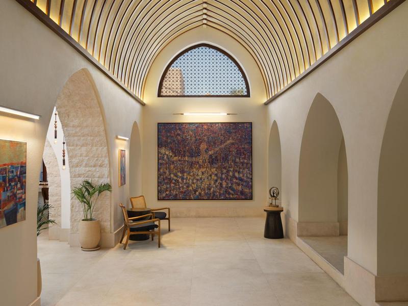 Vestíbulo de hotel luminoso con arcos altos, arte en las paredes y mobiliario minimalista.