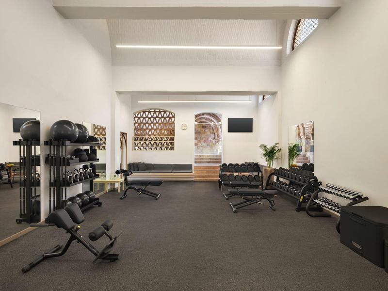 Gimnasio luminoso y minimalista con equipos y pesas en interior moderno de hotel.