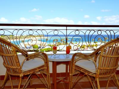 Balcone con due sedie in vimini e tavolo con bevande con vista mare.
