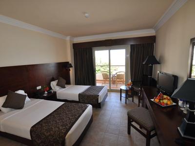 Camera d'hotel con due letti singoli, scrivania e balcone con vista sul verde.