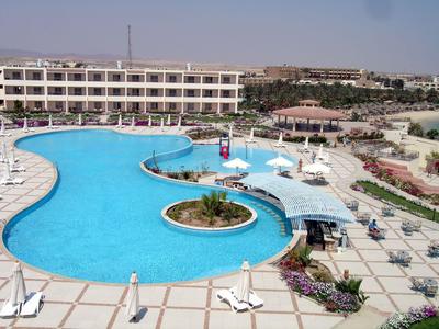 Complesso alberghiero moderno con grande piscina esterna curva e lettini al sole