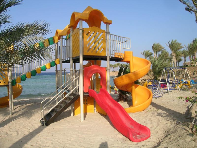 Parco giochi colorato con scivoli sulla spiaggia sotto un cielo blu