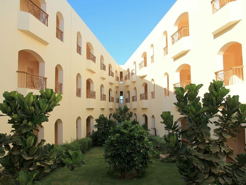 Cortile interno di un hotel a tre piani con piante e sole