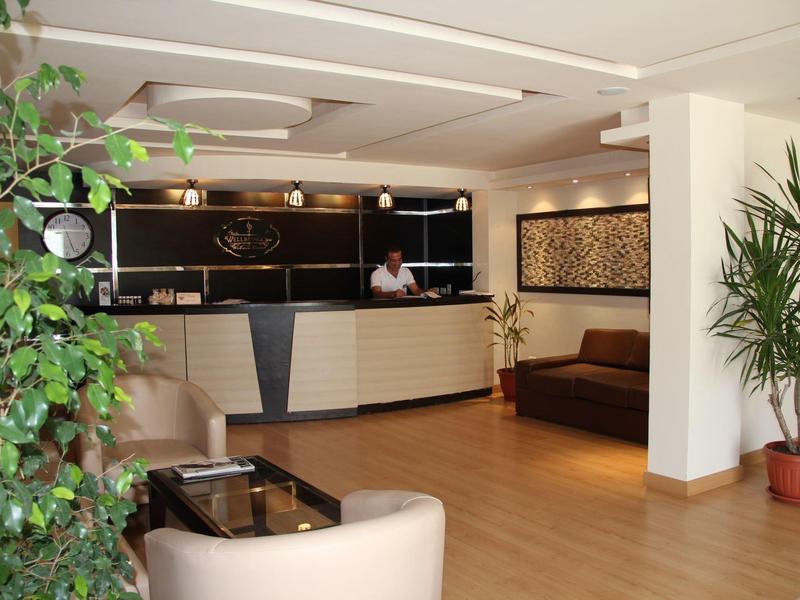 Moderna hall d'hotel con reception, area salotto e piante.