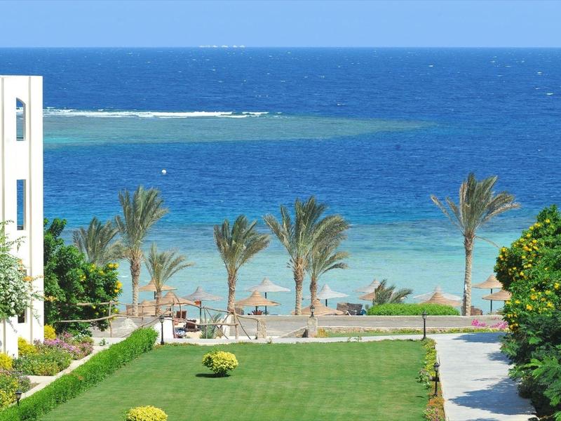 Vista da un giardino dell'hotel con palme sul mare blu e il cielo.