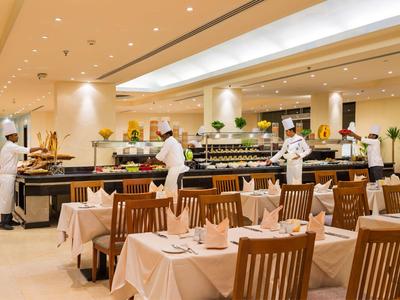 Elegantes Restaurant mit gedeckten Tischen und Kellnern in weißer Uniform an Buffets.