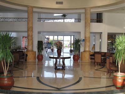 Großer heller Hotellobby-Bereich mit Marmorboden, Säulen und Pflanzen in Töpfen.