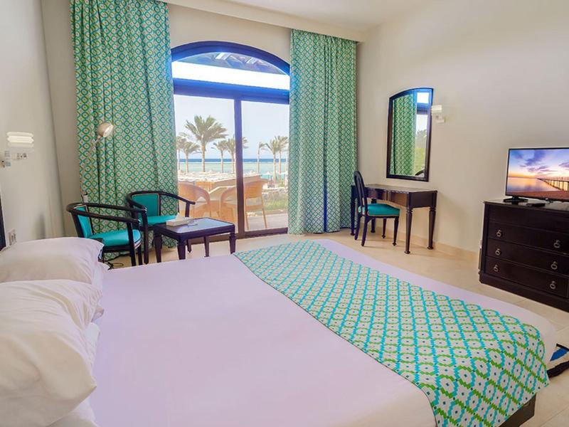 Jasny pokój hotelowy z łóżkiem podwójnym, balkonem i widokiem na morze w ciągu dnia.