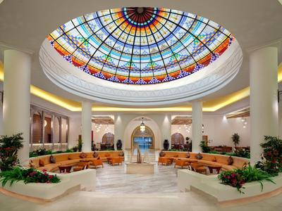 Bright hotel lobby with round colorful stained glass ceiling and beige seating areas