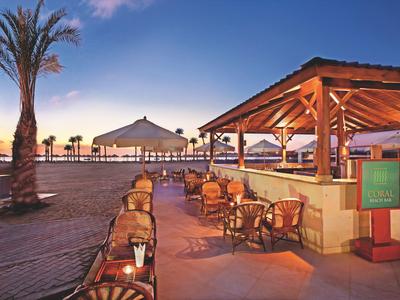 Open beach bar with chairs and tables outdoors at sunset.