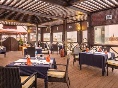 Covered restaurant terrace with set tables and rattan chairs.