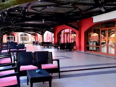 Terrasse couverte avec des sièges et des tables devant un restaurant aux murs rouges.