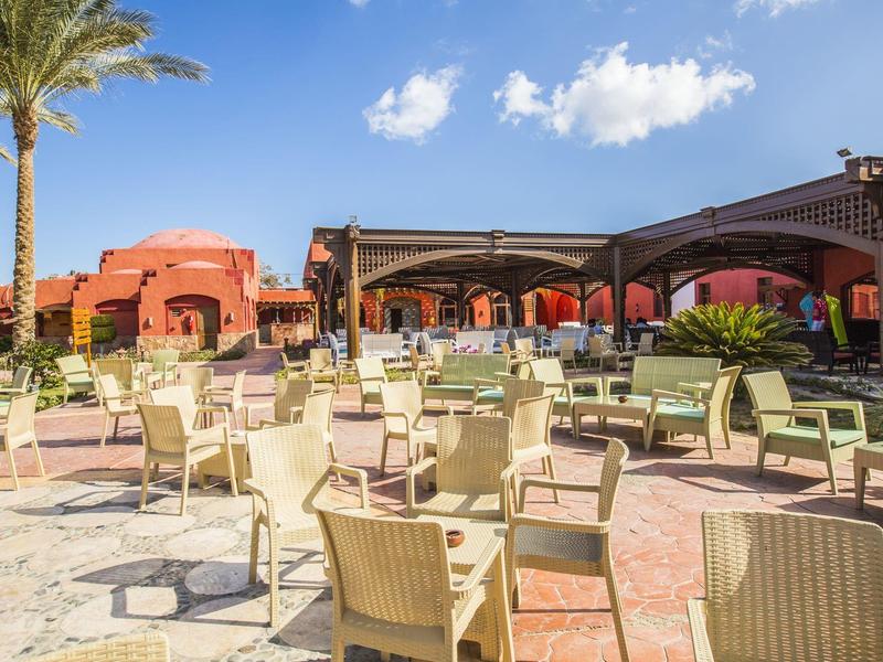 Espace extérieur d'un hôtel avec de nombreuses tables et chaises sous un ciel bleu