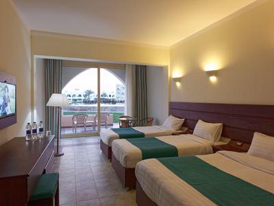 Moderner Hotelzimmer mit zwei Betten, Fernseher, Balkon und warmem Wandlicht.