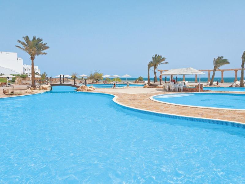 Grande piscina azzurra con palme e cielo sereno.