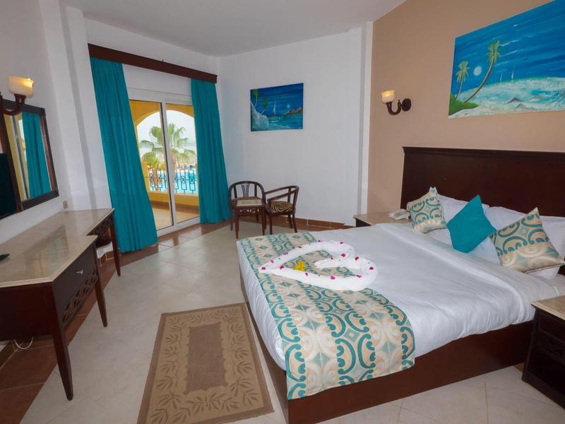 Moderní hotelový pokoj s manželskou postelí, balkonem a výhledem na moře.