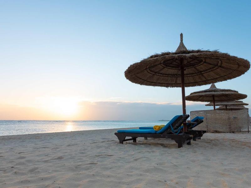 Beach with lounge chairs and umbrellas at sunset by the sea.