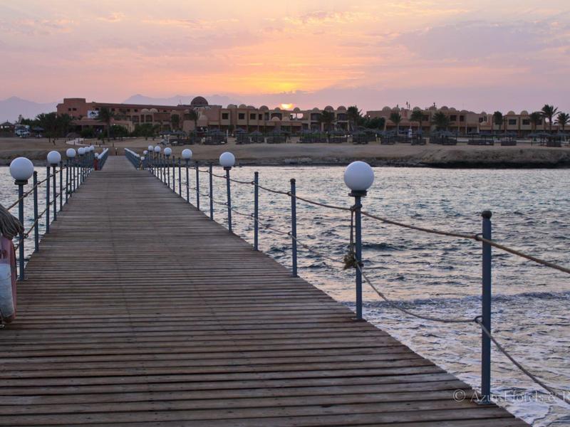 Ponton en bois s'étendant sur la mer sous un coucher de soleil coloré.